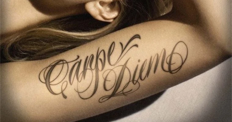Foto del brazo de una chica en el que vemos un tatuaje con la frase Carpe Diem