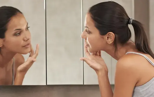 A Woman Checking Her Face on Mirror