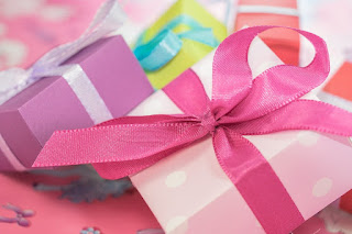 a small pile of brightly-colored square presents against a pink background