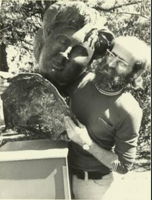 Bearded man's face next to sculpture of a man's face