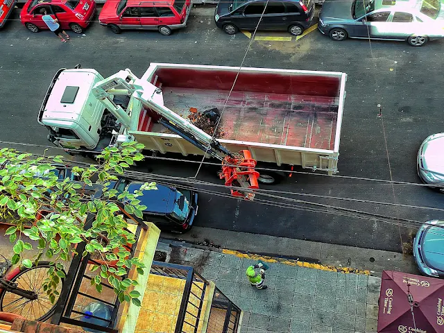 Brazo mecanico subiendo escombros a un camion.