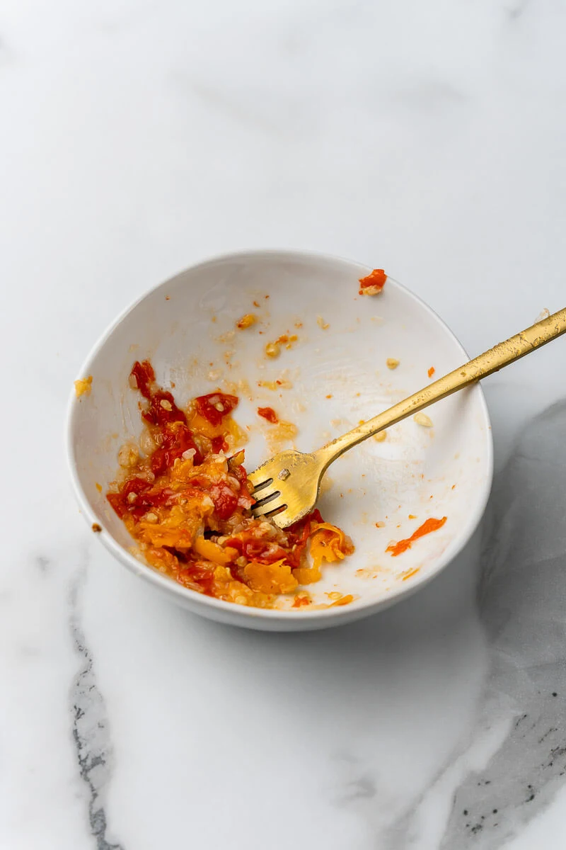 Image of crushed peppers and garlic in a white bowl.