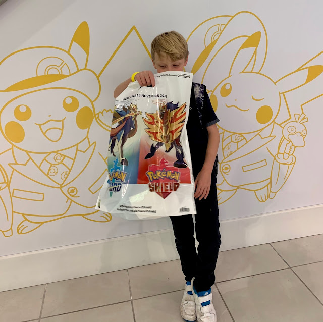 Inside Pokemon Centre London, child holds  Pokemon Sword and Shield shopping bag