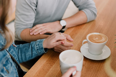 Pareja hablando tomados de la mano y delante de un café