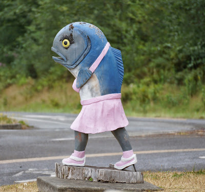 carving of a walking salmon is skirt, halter top, and sneakers