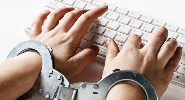 Two handcuffed hands typing on a keyboard (montage)