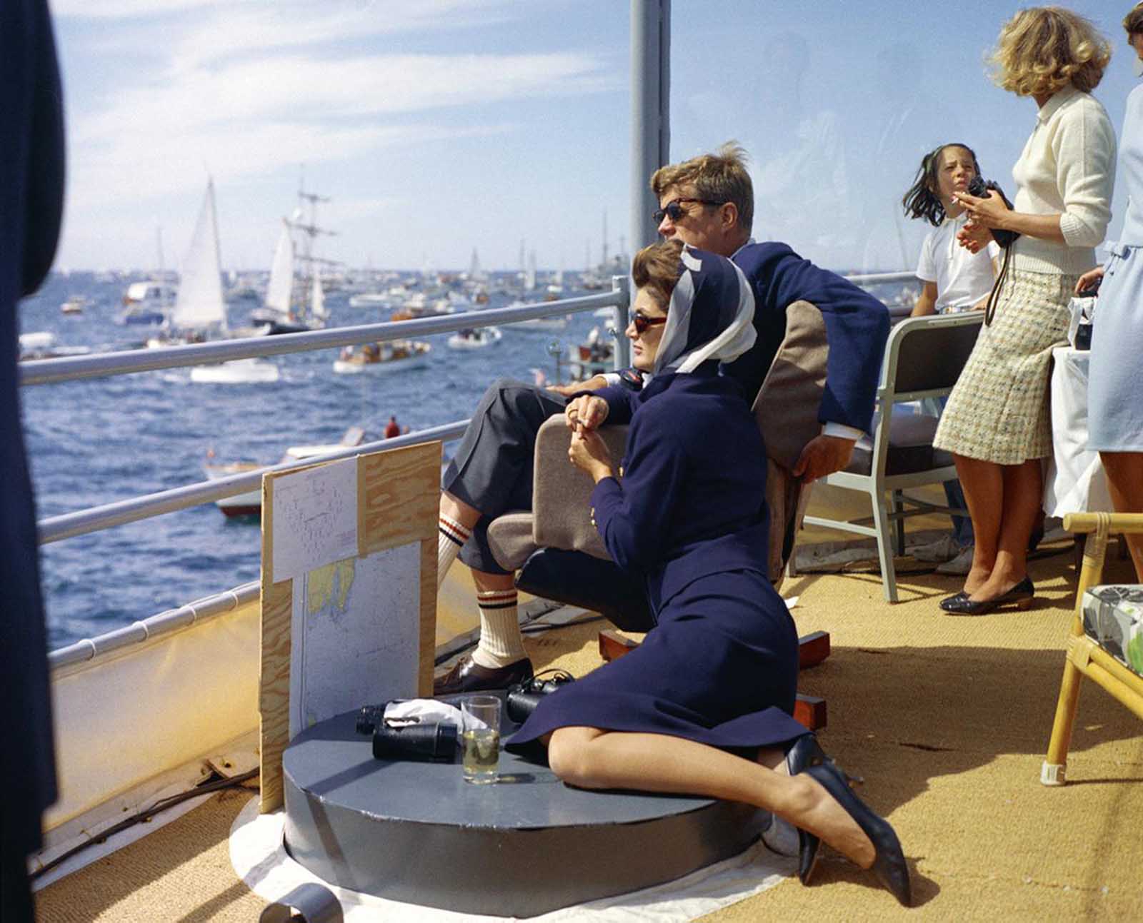 Aboard the USS Joseph P. Kennedy, Jr., named after the brother killed in World War II, President and Mrs. Kennedy watch the first race of the 1962 America's Cup competition off Newport, Rhode Island.