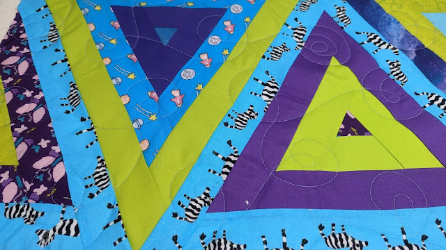 Modern triangle quilt made with fabrics designed by patients at St. Jude Hospital for JOANN stores