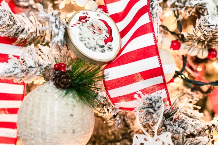 red and white beaded garland with Santa face wood slices hanging on tree