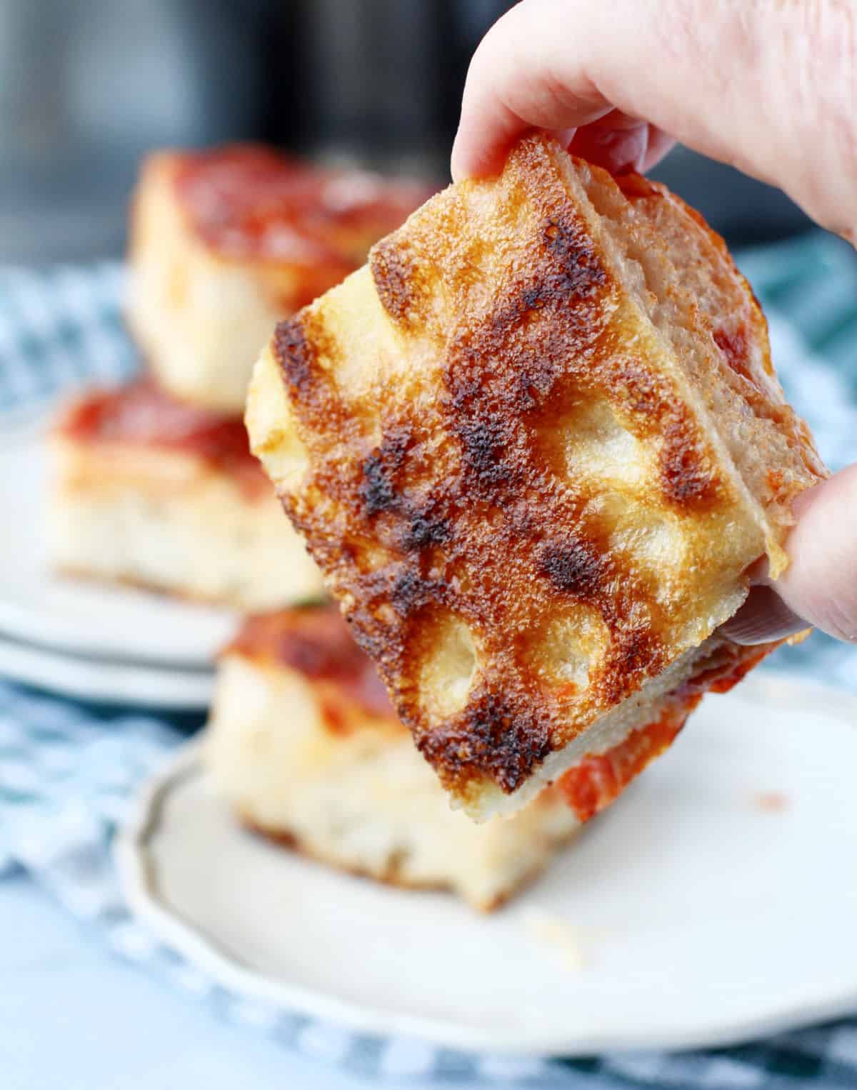 Pepperoni and Mushroom Pan Pizza Crust bottom being held by a hand.