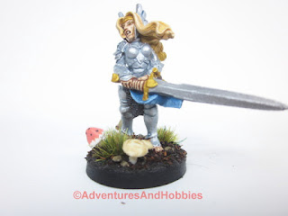Front view, slightly angeled from the side of a painted fantasy female elf warrior wielding a two-handed greatsword in 28mm scale for use in fantasy role-playing games and table top war games. Copyright Adventures And Hobbies.
