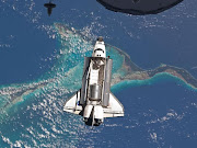 Here we see the space shuttle Atlantis over the clear blue waters of the . (space shuttle over bahamas)