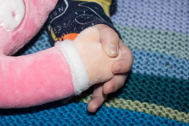 A baby holding the hand on Baby Annabell Sweetie