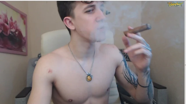 1/2 cute tattooed shirtless dude smoking a cigar from the chest up sitting inside an office chair