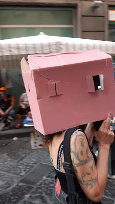 una manifestante con una casa di cartone sulla testa