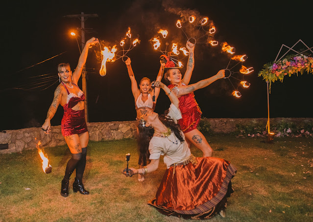 Artistas de circo com fogo recebem os convidados em festa de casamento na praia.