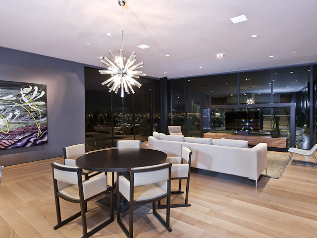 Photo of modern dining room and living room interiors at night with the city views through the windows