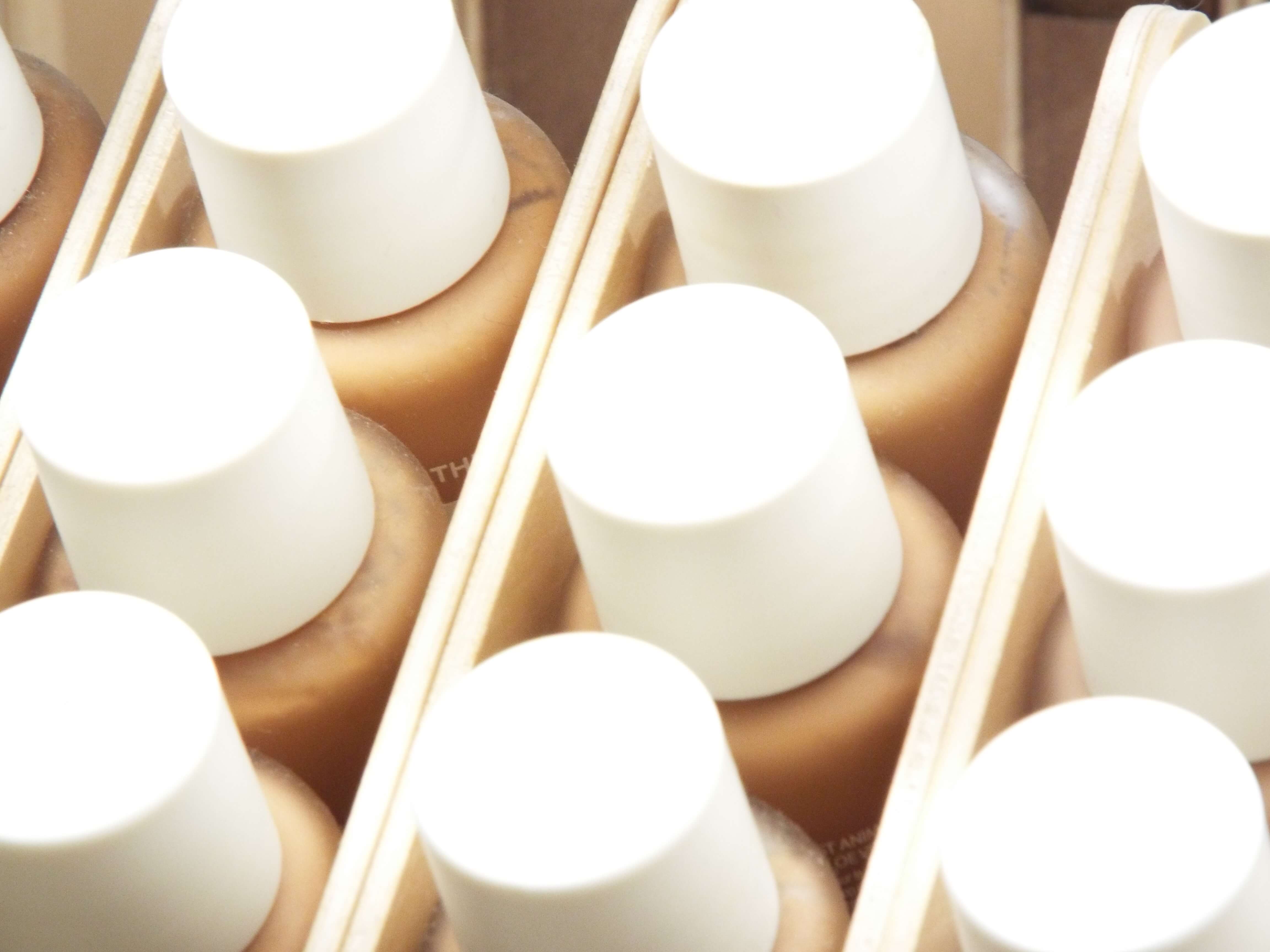 Array of glass bottle, white top foundations lined up on the makeup shelves, with soft focus lighting.