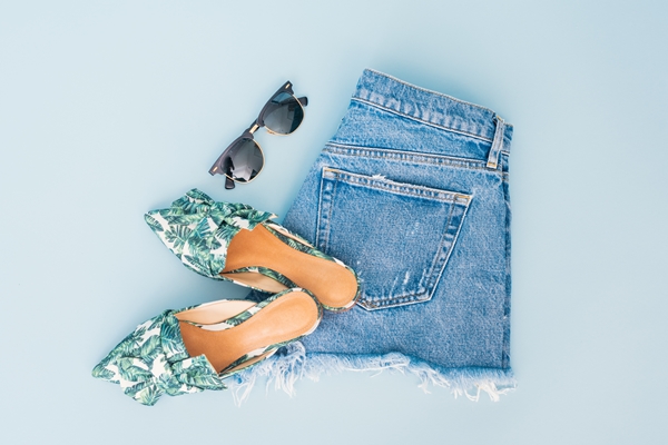 flatlay-shorts-dobrado-mule-e-oculos-de-sol-em-um-fundo-azul