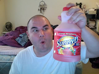 Guy drinking Sunny D Sunny Delight Orange Strawberry in dorm room with no sheets and dreamcatcher above bed 