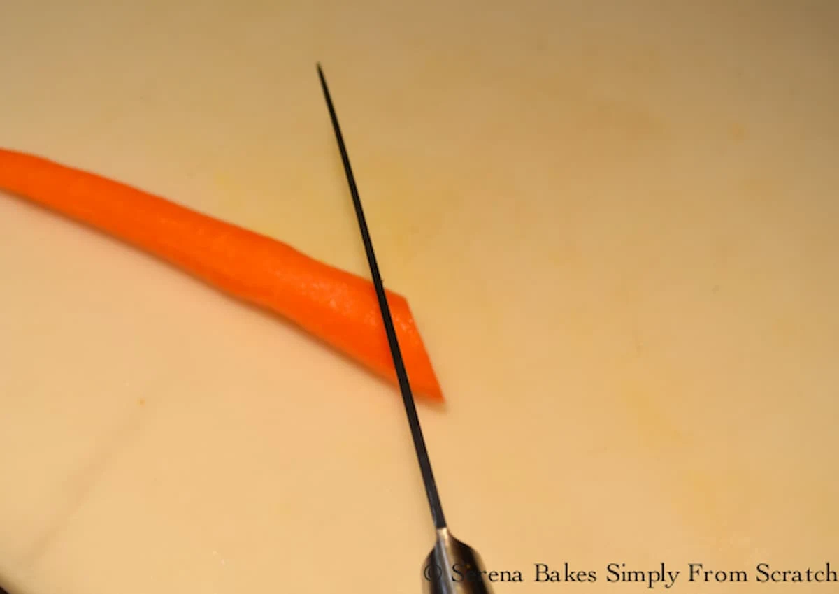 A carrot being cut with a knife on the bias.