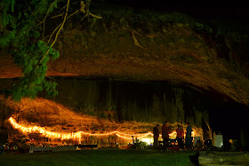 Night picture of people camping in big cave with Christmas Lights