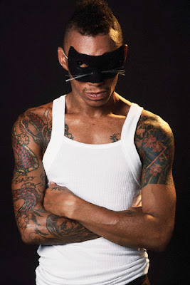 Black man with a mask, having sleeve dragon tattoo to chest.