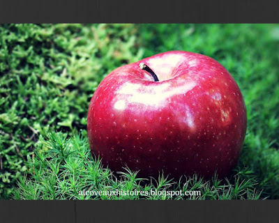 Une pomme ronde, rouge et brillante est posée sur un tapis de mousse verte.