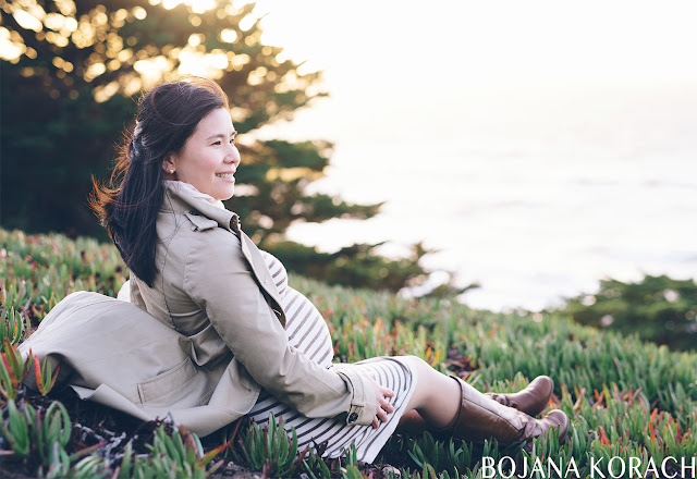 pregnant woman sitting on the ground at lands end in san francisco looking toward the ocean