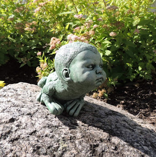 Creepy frog boy stone statue