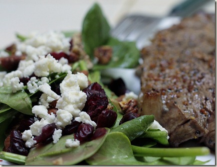 baby spinach salad with dried cranberries, chopped pecans, and feta cheese, drizzled with raspberry vinaigrette