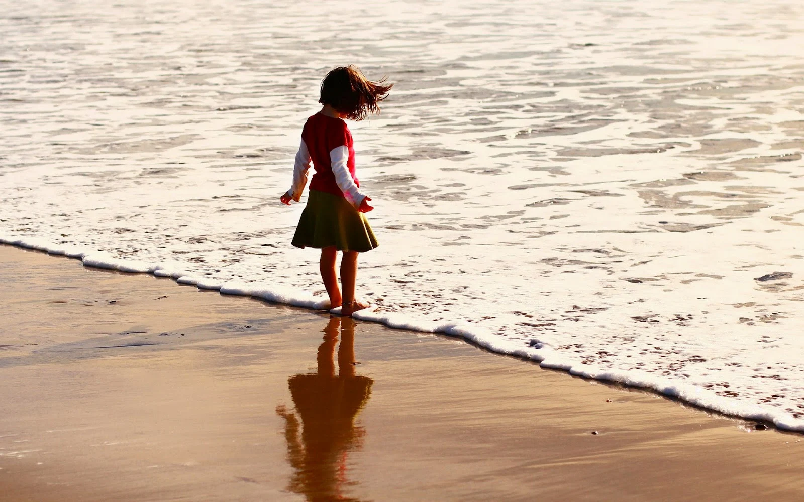 Meisje op strand in water van zee