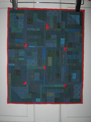 miniature improv quilt in blues, greens, teals with red triangles