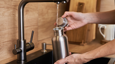 filling a stainless steel reusable water bottle up at sink