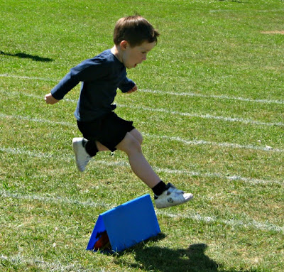Small boy jumping a hurdle at Sports Day