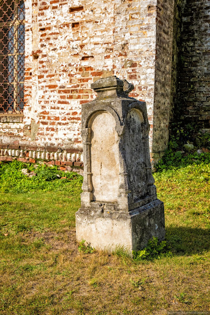 Надгробный камень у кирпичный стены церкви