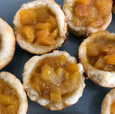 Apricot Tassies: cookies with a homemade apricot jam, baked in mini muffin cups. Multiple cookies photographed together in a container.