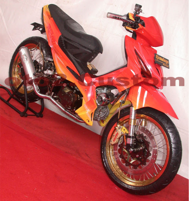 Foto Modifikasi Honda Revo dengan modif Racing Road Race didominasi warna yang mencolok yakni oranye dan sedikit warna kuning dibagian bawah bodi motor untuk belakang jok dibuat meruncing tak lupa jari-jari dibuat rapat lurus untuk pada bagian velg diwarna oranye kesekujur lingkar pelek