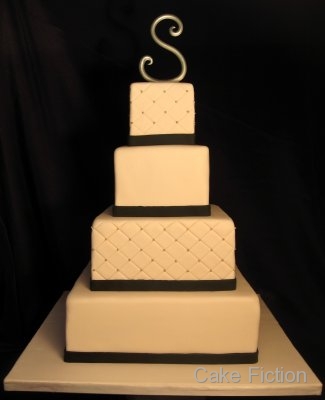 A four tier quilted diamond ivory wedding cake with black fondant ribbons