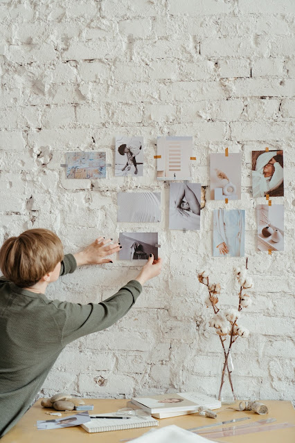 A person putting up pictures on a white wall for their vision board.