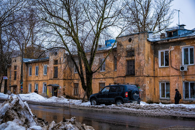 Старое ветхое здание с башенками над подъездами