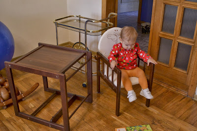 a small girl is sitting on the chair and playing in the living-room