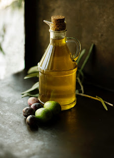a bottle of olive oil with a few olives on the side