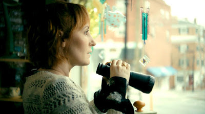 Love in Kilnerry 2019 indie movie still featuring Kathy Searle looking out a window with binoculars