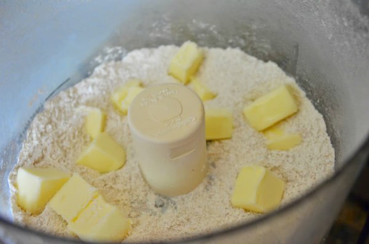 Chopped Almonds, Flour, Powdered Sugar, Salt in a food processor topped with cubes of butter.