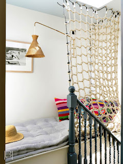 Beata Heuman hallway sitting area with ticking stripe cushion, bright pillows, a rattan light, and fish net