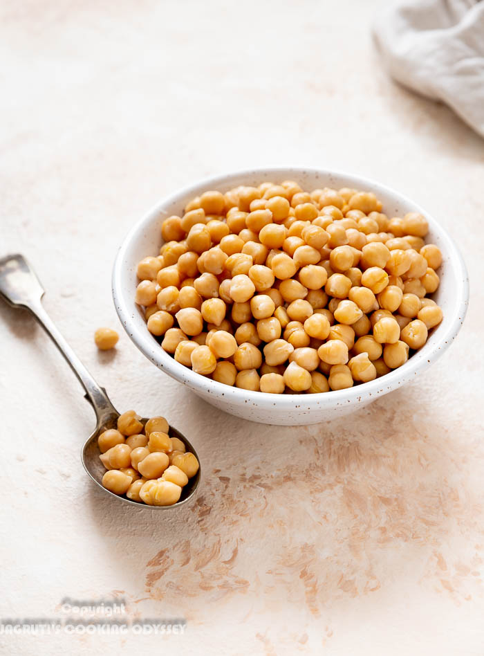 Instant pot cooked chickpeas in a beige bowl with a spoon