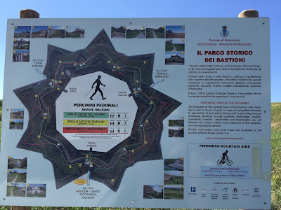 Palmanova sign explaining walking and biking routes and distances.