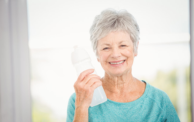a smiling old woman holding a bottled water