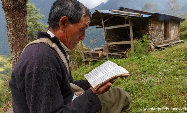 Hombre asiático leyendo la Biblia en el campo